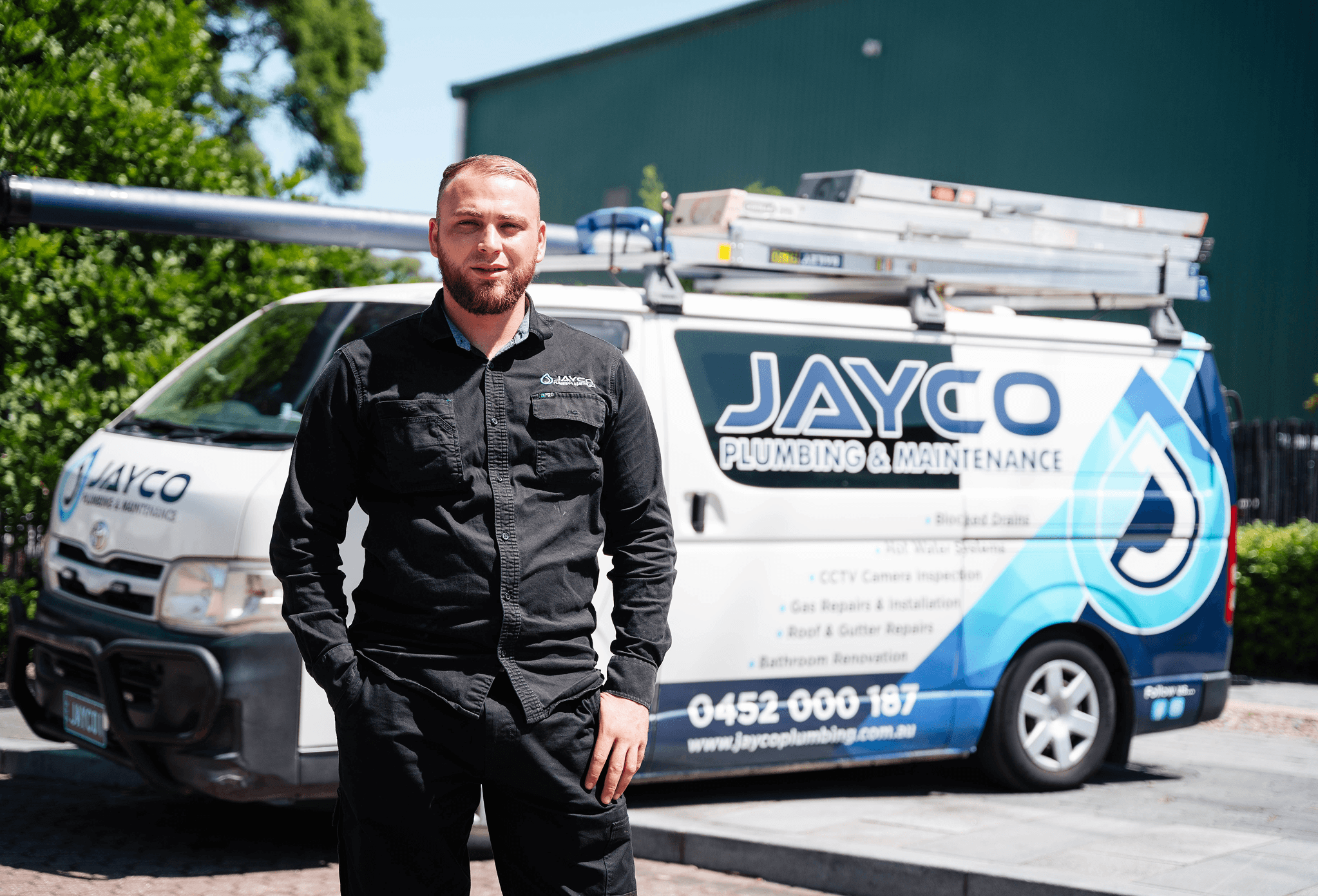 Jayco plumber standing beside a branded service van